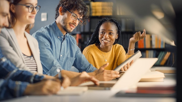 Étudiants dans une bibliothèque, l'un d'eux utilise une tablette.