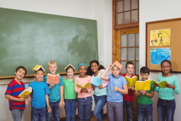 Étudiants debout avec des livres sur leur tête à l&#39;école primaire