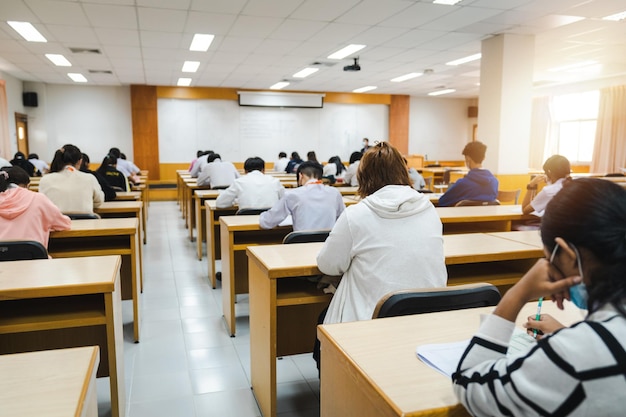 Étudiants du Collège écrivant sur des papiers d'examen final en classe avec concentration