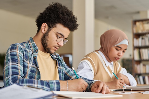 Étudiants multiethniques écrivant un examen de langue étrangère à table en classe