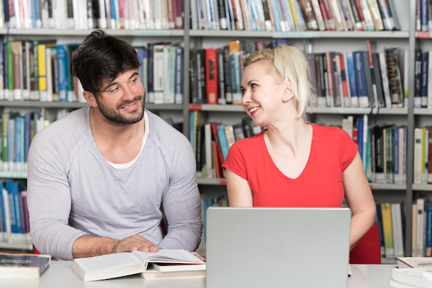 Étudiants préparant l'examen et apprenant des leçons dans la bibliothèque de l'école faisant des recherches sur un ordinateur portable et naviguant sur Internet dans la bibliothèque