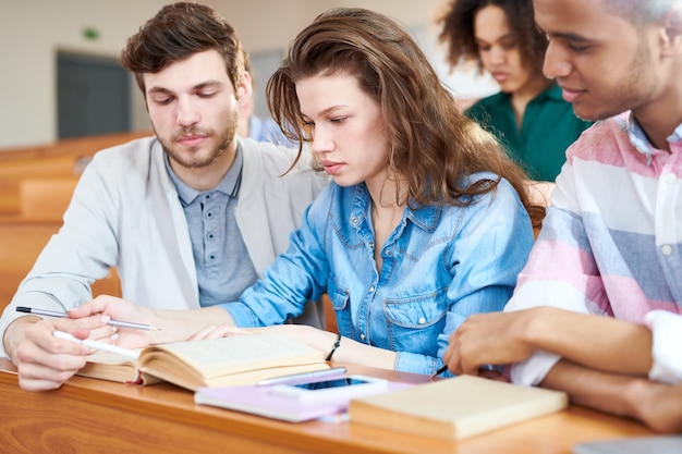 Étudiants sérieux apprenant des informations d'un manuel