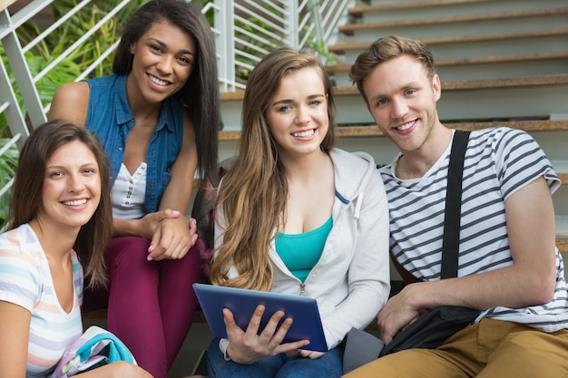 Étudiants souriants assis sur les marches avec tablet pc