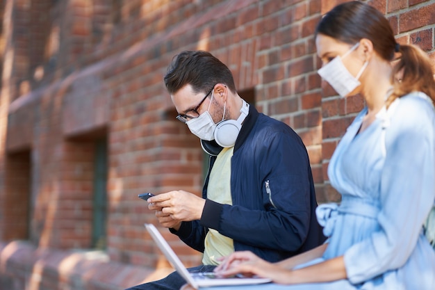 Étudiants traînant sur le campus portant des masques de protection et gardant la distance en raison de la pandémie de coronavirus