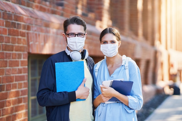 Étudiants traînant sur le campus portant des masques de protection et gardant la distance en raison de la pandémie de coronavirus