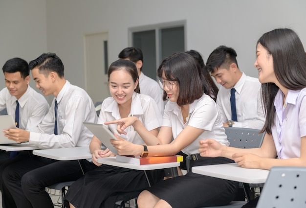 Étudiants en uniforme travaillant avec tablette en salle de classe