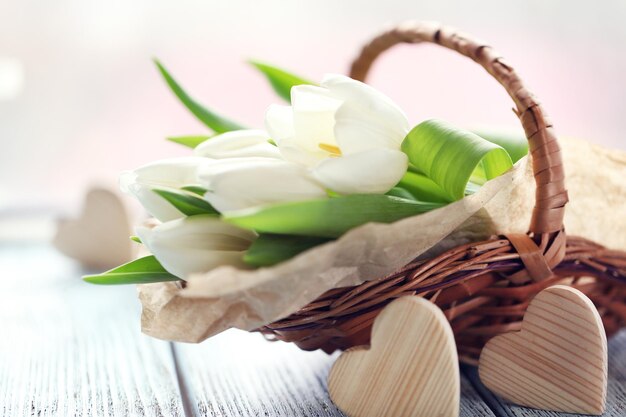 Tulipes blanches dans un panier en osier sur une table bleu clair