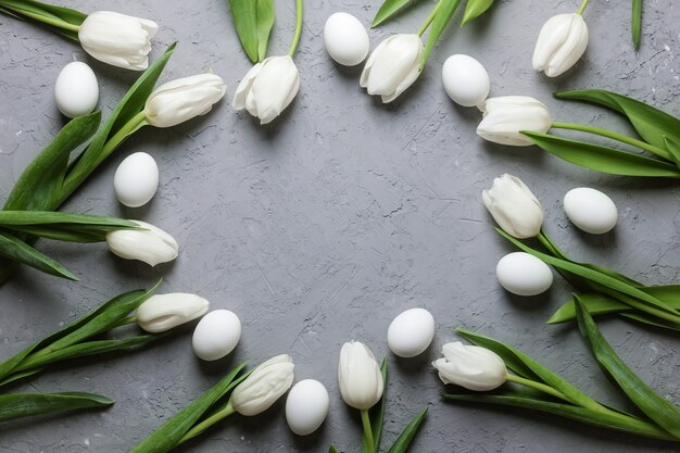 Tulipes blanches avec des œufs sur fond de béton gris