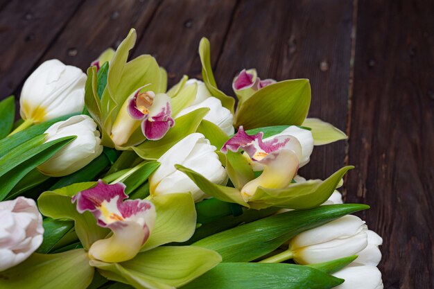 Tulipes blanches et orchidées vertes sur une table en bois foncé