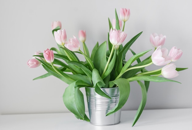 Tulipes blanches de printemps dans un vase abstrait sur l'étagère, salle intérieure
