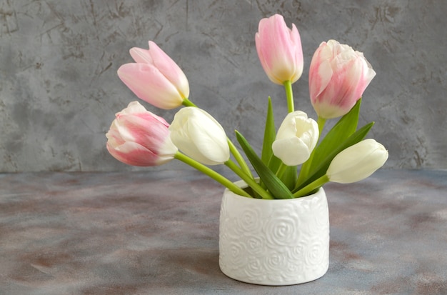 Tulipes blanches et roses dans un vase blanc.