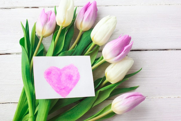 Tulipes blanches et violettes sur un fond en bois blanc