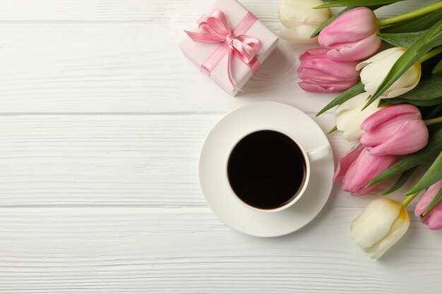 Tulipes, café et coffret cadeau sur fond en bois blanc, espace pour le texte