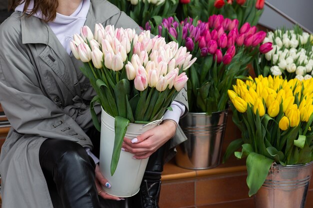 Tulipes de couleur rose dans la main de la femme Jeune belle femme tenant un bouquet de printemps sur fond de fleur Bouquet de fleurs de printemps fraîchement coupées dans les mains des femmes Concept de magasin de fleurs