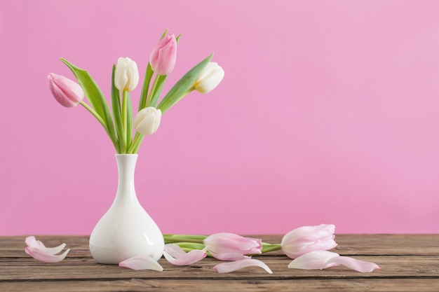 Tulipes dans un vase blanc sur fond rose