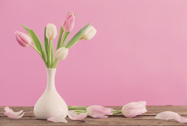 Tulipes dans un vase blanc sur fond rose