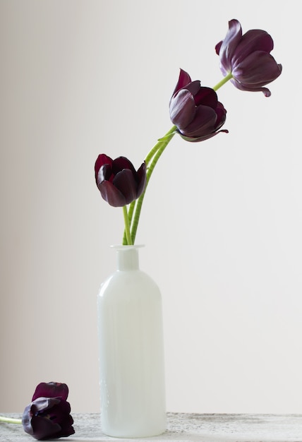 Tulipes dans un vase blanc sur une table en bois