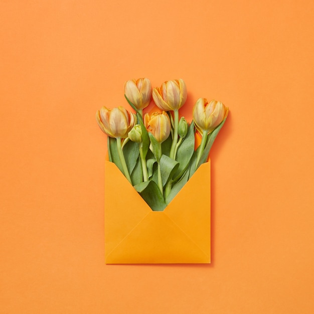 Tulipes De Fleurs Fraîches De Printemps Dans Une Enveloppe Artisanale Sur Fond Jaune Avec Espace De Copie. Lettre D'amour Pour Félicitation. Mise à Plat