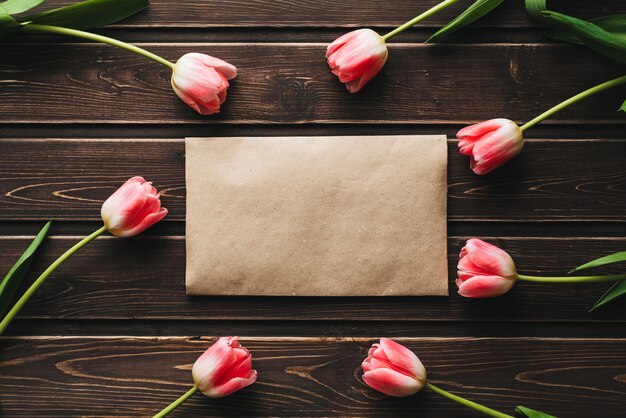 Tulipes de fleurs roses avec une enveloppe postale en papier sur une table en bois