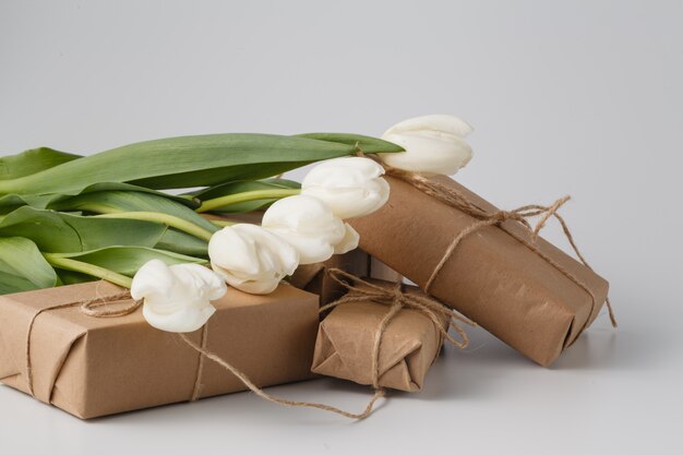 Tulipes fraîches et coffret cadeau sur une surface blanche