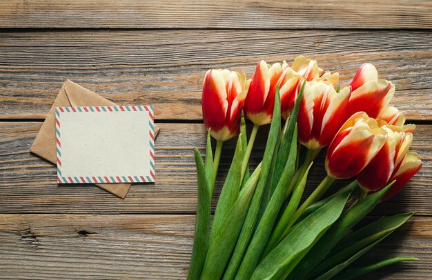 Des tulipes fraîches sur fond de bois avec de l'espace pour un texte plat sur une carte de vœux