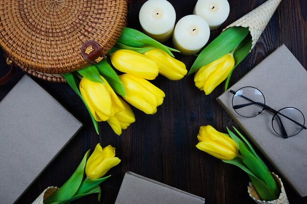 Tulipes jaunes confortablement disposées sur la table dans un sac en osier et dans des cornets gaufrés