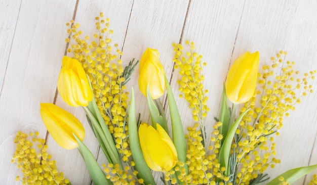 Tulipes et mimosa sur fond de bois blanc