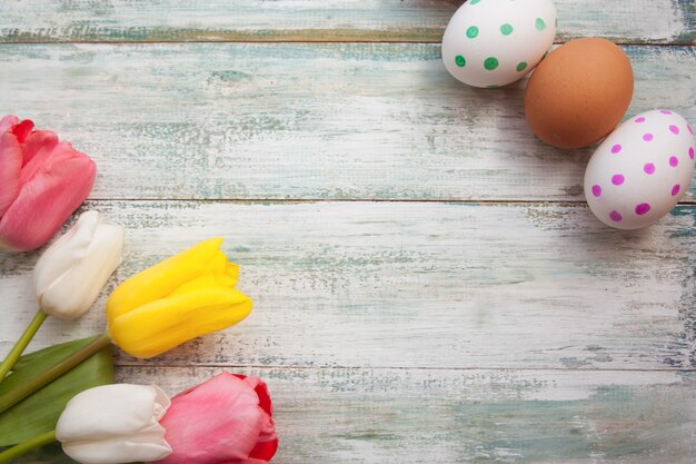 Tulipes et oeufs de Pâques sur un fond clair shabby vintage, vue de dessus, fond vide.