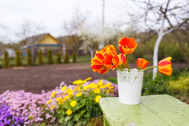 Tulipes orange dans un vase sur la table dans le contexte de la nature.