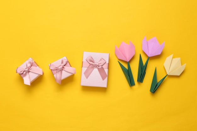 Tulipes origami faites à la main et coffrets cadeaux sur fond jaune 8 mars concept de la journée de la femme Vue de dessus Minimalisme