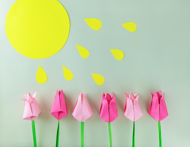 Des tulipes en papier coloré avec le soleil sur un fond vert appliqué artisanal à la main