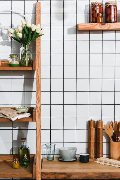 Tulipes en pot de verre sur des étagères en bois avec des bouteilles et des tomates en conserve