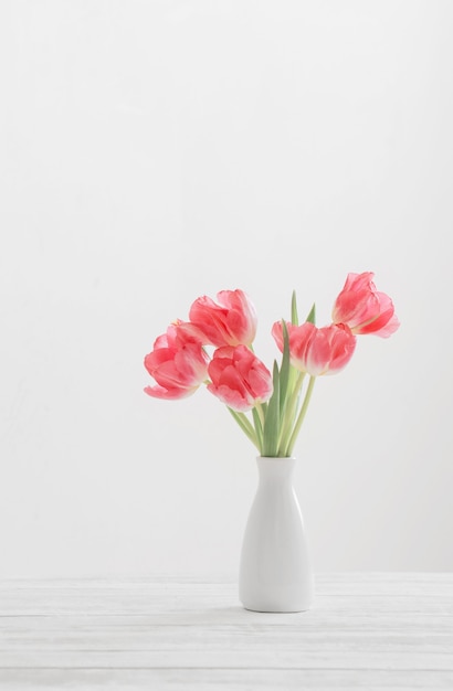 Tulipes de printemps dans un vase blanc sur une surface blanche