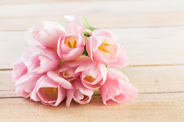 Tulipes rose clair sur fond de bois.