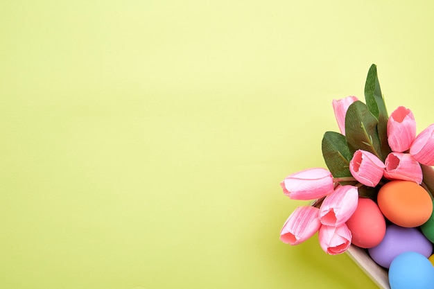 Tulipes roses en boîte et oeuf de Pâques sur jaune