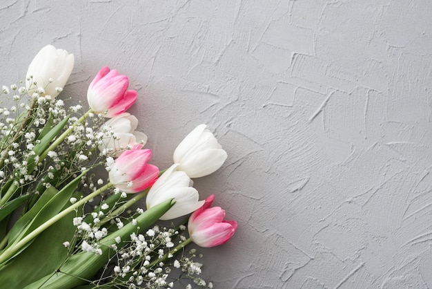 Photo tulipes roses et bouquet de fleurs de gypsophile blanc sur un élégant fond de pierre grise concept de célébration d'anniversaire de la fête des mères copier l'espace pour la maquette de texte