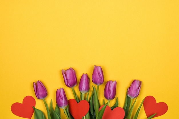 tulipes roses et coeurs rouges sur mur jaune