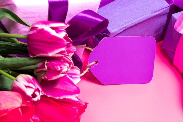 Tulipes roses délicates et coffrets cadeaux avec une étiquette avec une place pour le texte