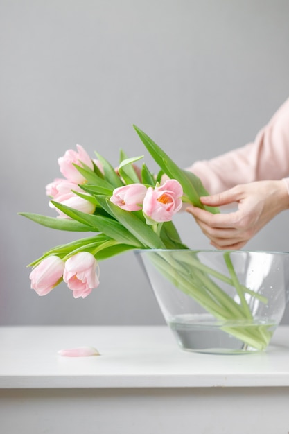 Tulipes roses avec des feuilles vertes dans un vase en verre