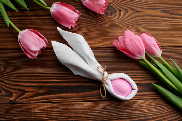 Tulipes roses et oeuf de Pâques sur table en bois. Fleurs de printemps en fleurs et nourriture pascale, décoration florale fraîche pour la célébration des vacances