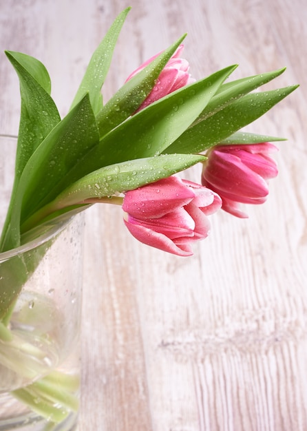 Tulipes roses en pot de verre sur table en bois