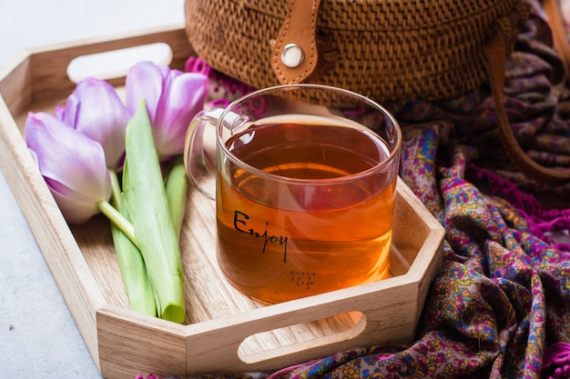 Tulipes roses et une tasse de thé sur un plateau en bois