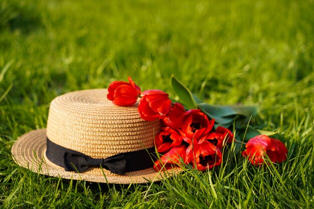 Tulipes rouges avec chapeau de paille sur l'herbe verte. photo de haute qualité
