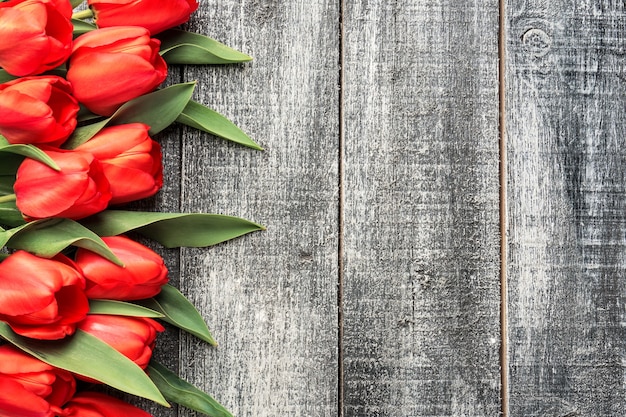 Tulipes rouges sur fond de bois noir et blanc, vue de dessus plat