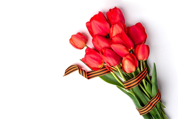 Tulipes rouges avec ruban St. George sur fond blanc. Jour de la victoire ou jour du défenseur de la patrie.