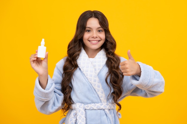 Tunny nez et allergie spray nasal Teen girl in pajama utiliser des gouttes nasales nez farci isolé sur fond jaune