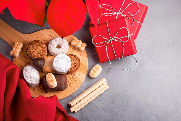 Turron de bonbons de Noël traditionnels espagnols, polvorones, mantecados avec décor de Noël et coffrets cadeaux rouges sur table grise, espace pour copie