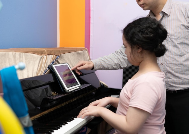 Un tuteur apprend à une fille à jouer du piano