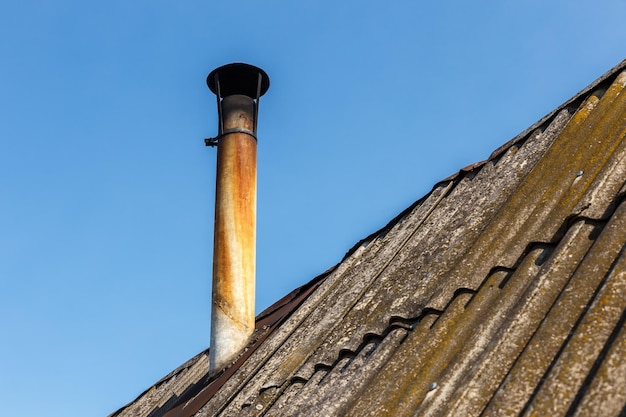 Tuyau de cheminée sur le toit de la maison contre le ciel bleu