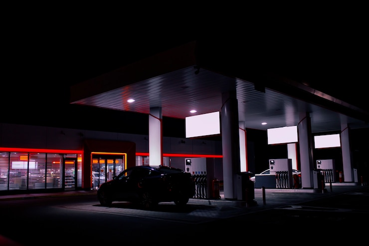 Photo un tuyau de gaz est installé dans une voiture dans une station-service de nuit avec un magasin de lumières vives.